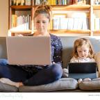 picture of parent working from home on the sofa next to their child
