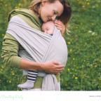 picture of a woman with a baby sleeping in a sling outdoors in nature