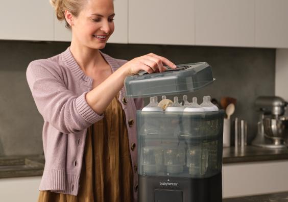 a mum in a kitchen using a Baby Brezza SuperQuick Steriliser Dryer picture of a mum in a kitchen using a Baby Brezza SuperQuick Steriliser Dryer