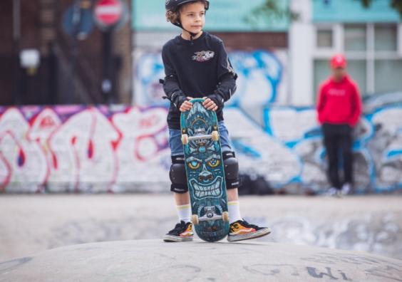 a child with a skateboard and helmet at a skatepark picture of a child with a skateboard and helmet at a skatepark