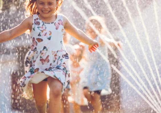 picture of a happy child running through a sprinkler on a hot summer day in the garden