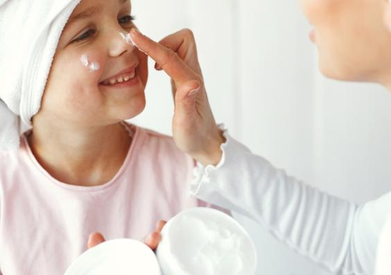 a happy child who suffers from dry skin having lotion put on her face picture of a happy child who suffers from dry skin having lotion put on her face