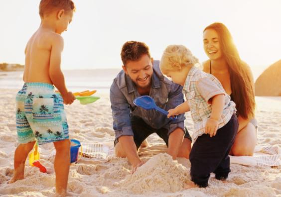 picture of a happy family on a beach building a sandcastle whilst on holiday