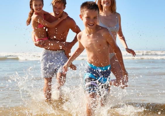 picture of a happy family running through the sea whilst on holiday