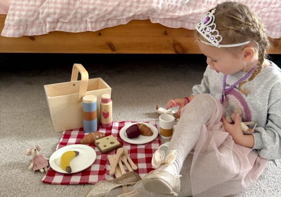 picture of a child playing imaginatively with a wooden tea set in a beautiful bedroom