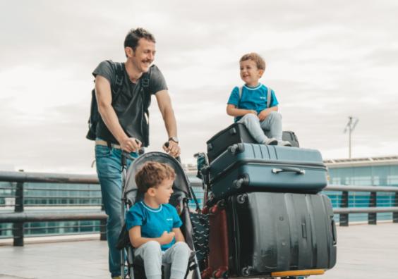 picture of a dad at an airport with his two children and lots of suitcases moving abroad