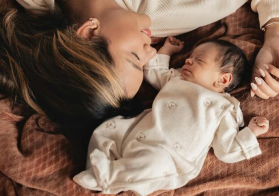 picture of a mum laying with her newborn baby on a brown blanket