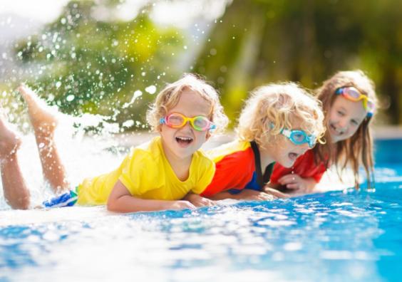 picture of happy children in brightly coloured swimwear by a pool