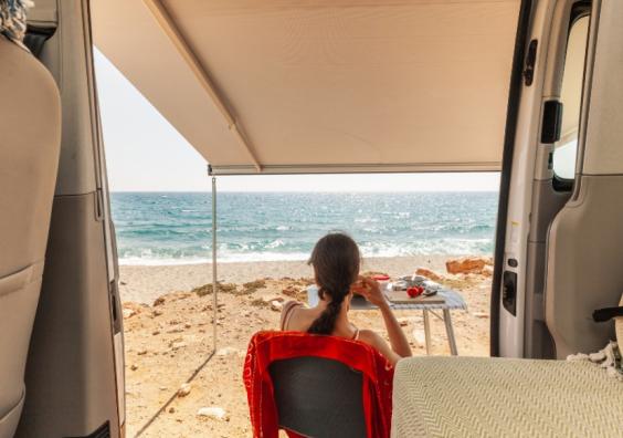 picture of a woman sat outside a caravan with a sunny beach scene