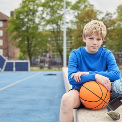 picture of a boy sat on a wall with a basketball