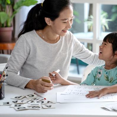 Picture of a happy mum and child sat at a table learning about letters