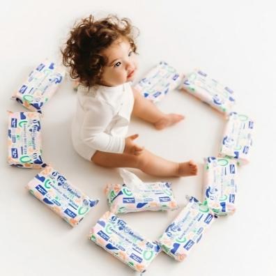 picture of a baby sat on the floor surrounded by Mo and Marine baby wipes