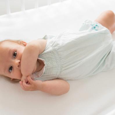 picture of a happy baby laying on a Hippychick fitted bedsheet