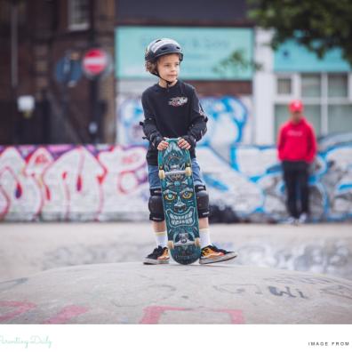 picture of a child with a skateboard and helmet at a skatepark