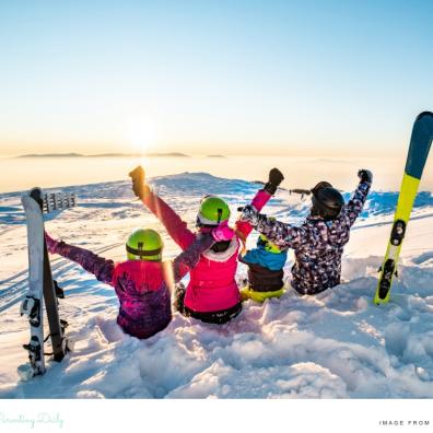 picture of a family on a ski holiday sitting in the snow looking at the sun set