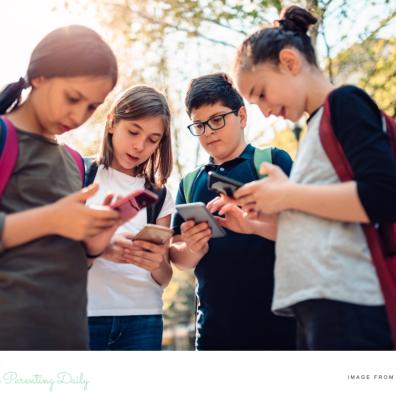 a group of children outside looking at their smartphones picture of a group of children outside looking at their smartphones
