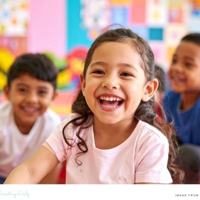 picture of a happy child in a classroom with other happy children behind her