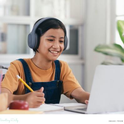 picture of a happy child wearing headphones and using a laptop for online learning