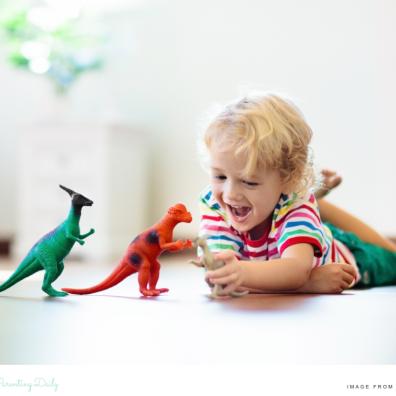 picture of a happy toddler playing with dinosaurs and practising animal sounds