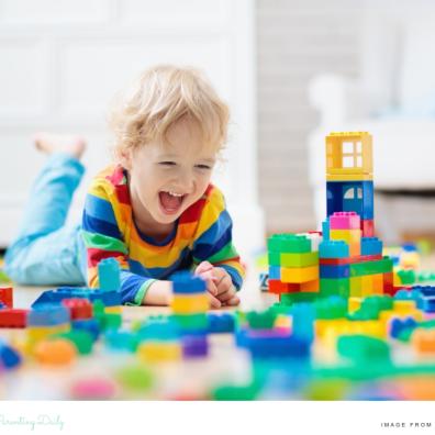 picture of a happy toddler playing with lots of colourful building blocks
