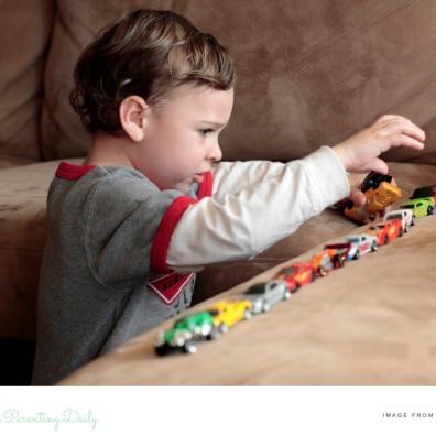picture of an autistic child lining their toy cars up on a sofa