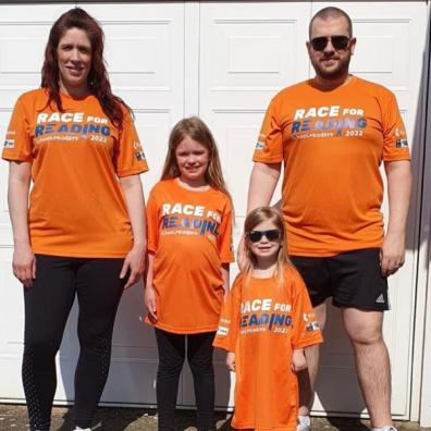 picture of a family wearing race for reading tshirts