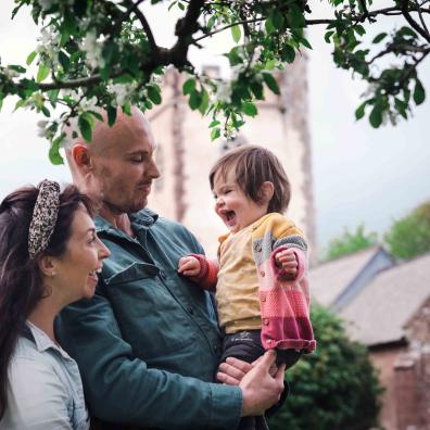 dad holds giggling little girl while mum pulls faces