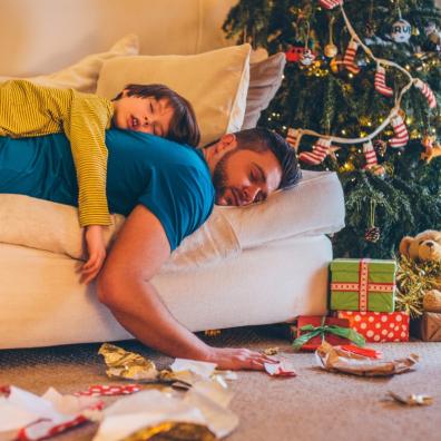 picture of a Father and son asleep on the sofa suffering Christmas burnout