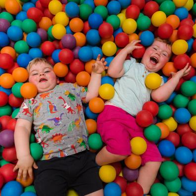 Two children lying in a ball pit at Dinomite Indoor Soft Play at ROARR!