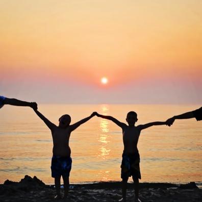 Family standing in front of a sunset at the beach