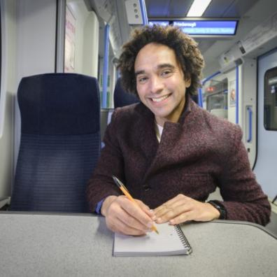 picture of Joseph Coelho writing a poem on a train