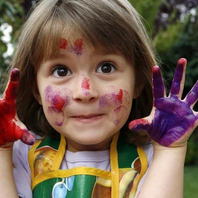 picture of a happy girl with paint on her hands and face