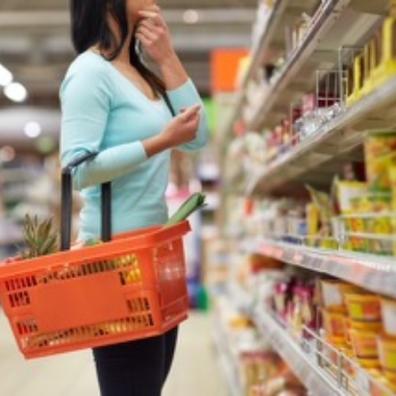 Picture of a woman with a basket in a supermarket shopping isle