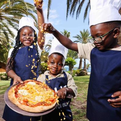 picture of children putting cornflakes on a pizza
