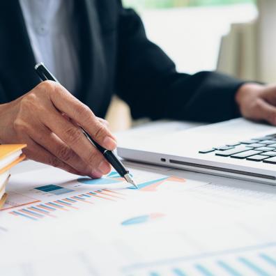 Picture of someone creating a report with a graph and a laptop