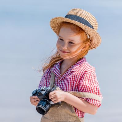 Picture of red headed child smiling holding a camera