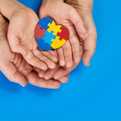 picture of an adult and childs hands holding a jigsaw puzzle heart