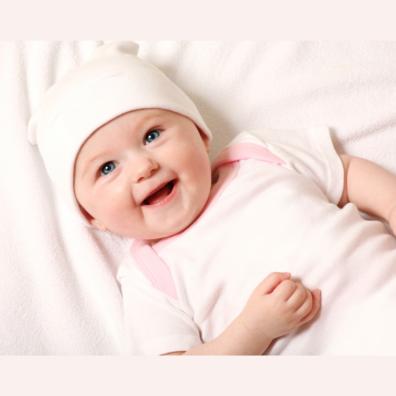 picture of happy baby with a pink baby grow and blanket