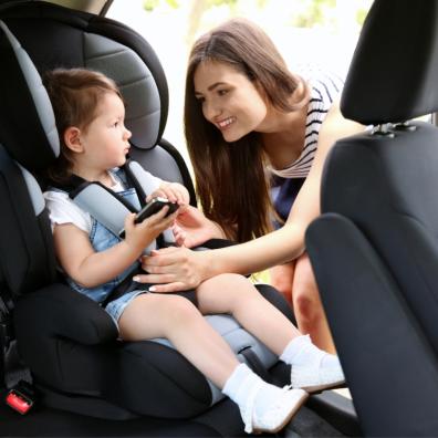 picture of a mum strapping her child into a car seat with a mobile phone
