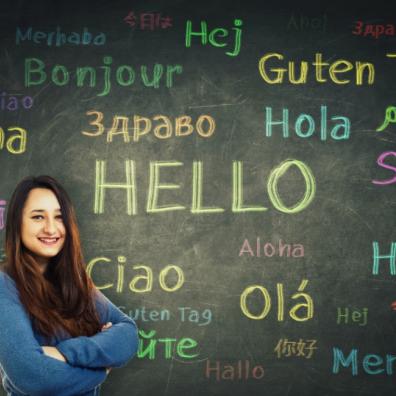 picture of a girl stood in front of a chalkboard with hello written in lots of different languages
