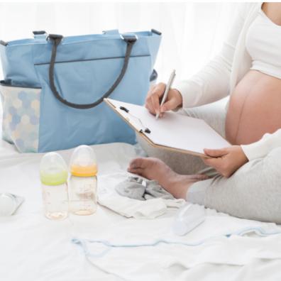 picture of a pregnant woman sat on a bed packing her hospital bag