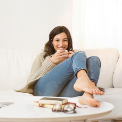 picture of a woman relaxing on the sofa with a drink and book