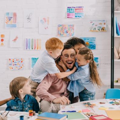 picture of students hugging a happy teacher