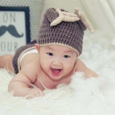 picture of a happy baby wearing a hat on a white rug