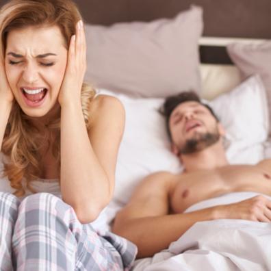 picture of a woman screaming as her partner snores in bed