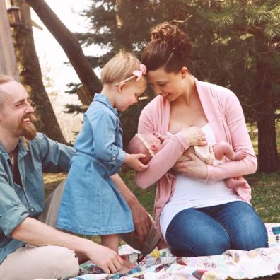 picture of newborn baby and family outside on a picnic blanket