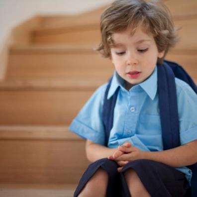 picture of a young boy sitting on the stairs in school uniform