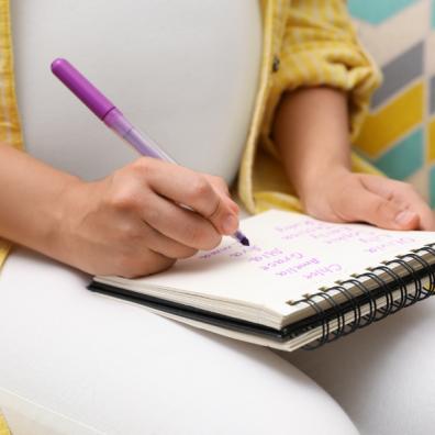 picture of pregnant woman writing a list of baby names