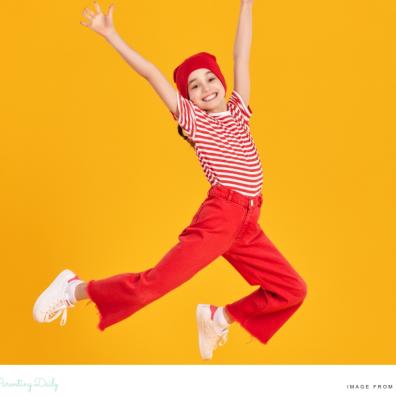 picture of a happy emotionally resilient child wearing red and jumping in the air