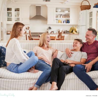 picture of a happy family with parents and two teenagers chatting happily at home on the sofa